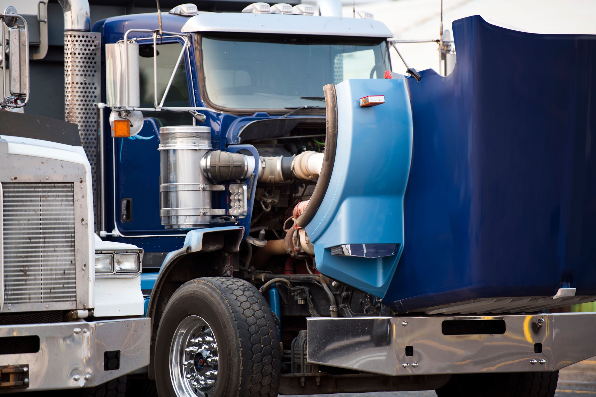 Camion semi bleu gros camion avec capot ouvert se tenant debout sur le terrain de stationnement pour travaux de réparation moteur et service