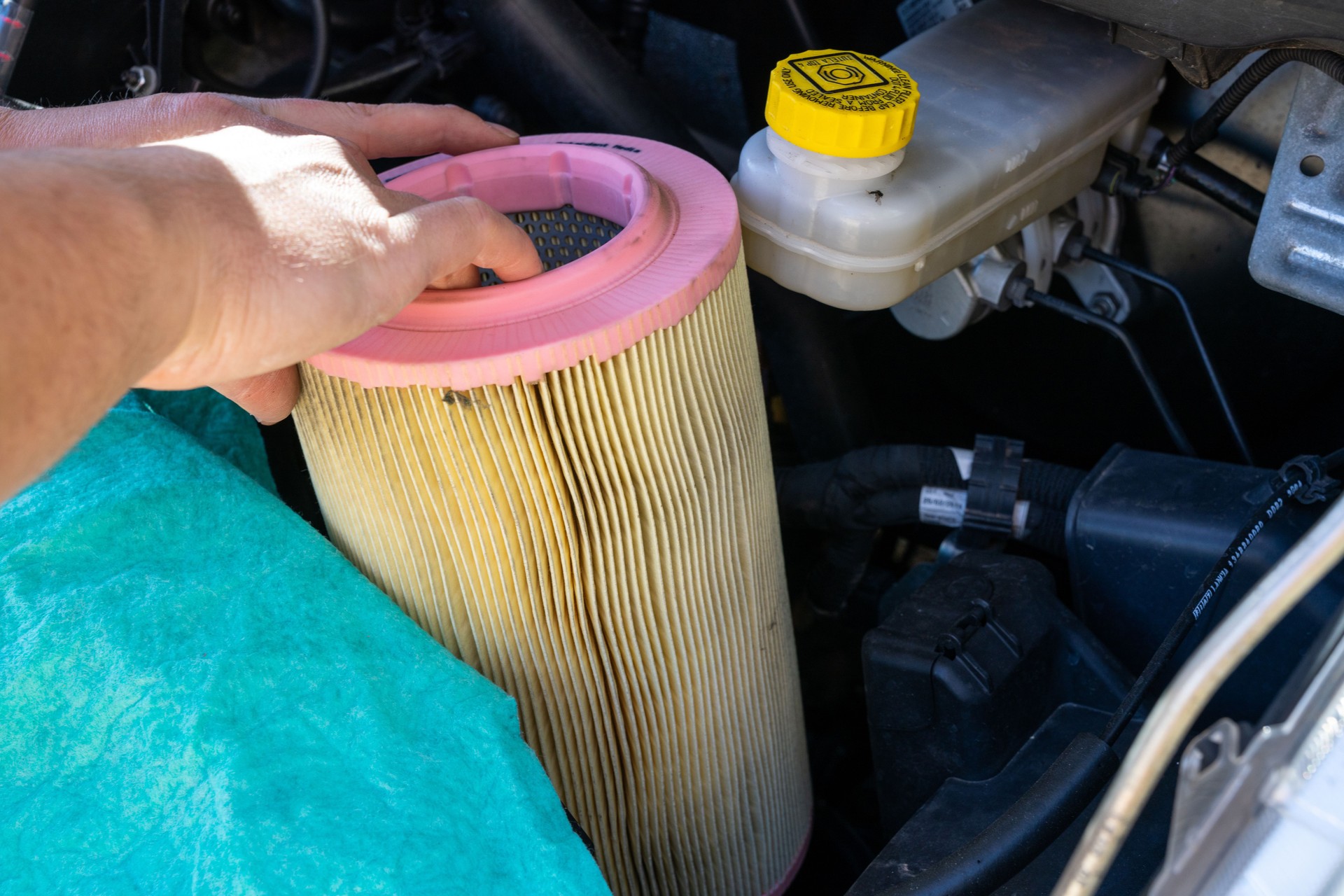 fermez-vous vers le haut des mains d’un mécanicien masculin caucasien de voiture changeant le filtre à air dans un moteur